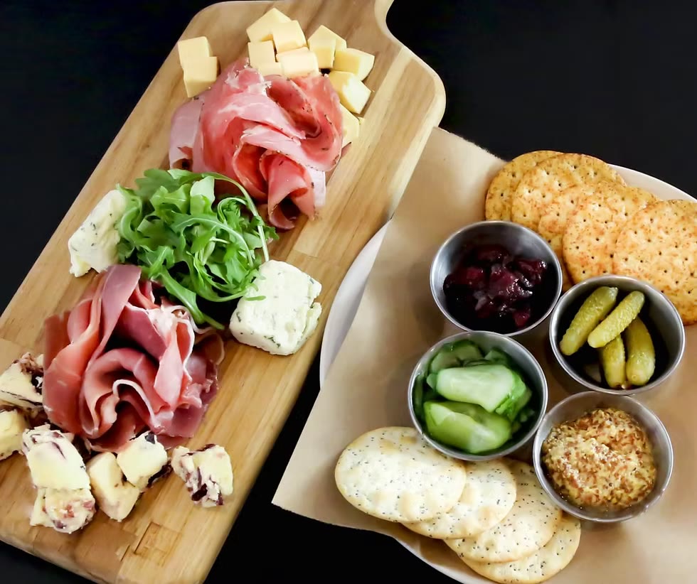 Artisanal cheese and charcuterie board with prosciutto, cheese, arugula, and pickled vegetables at Bistro 22